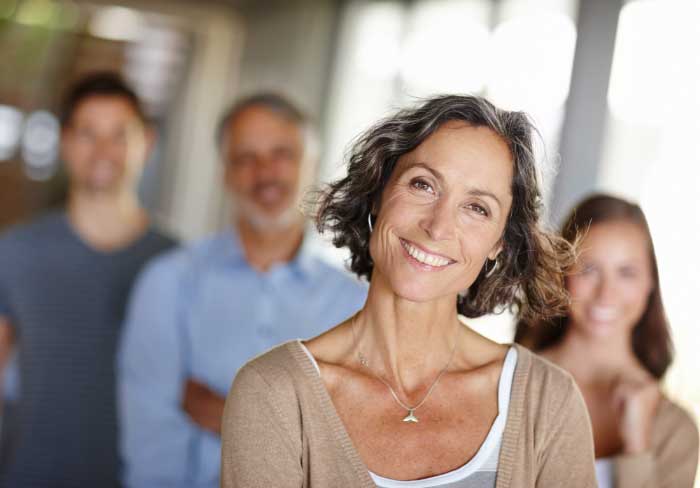 A female Special Education Teacher with three colleagues standing behind her, all smiling and looking at the camera